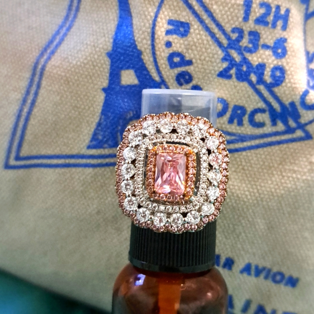 A beautiful ring, pink center stone with a small halo of pink stones.